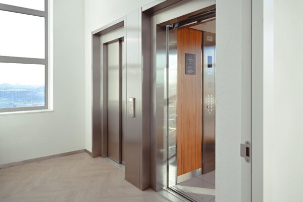 Twee moderne liften in een licht trappenhuis van het Rivium Quadrant, waarvan één met open deuren.